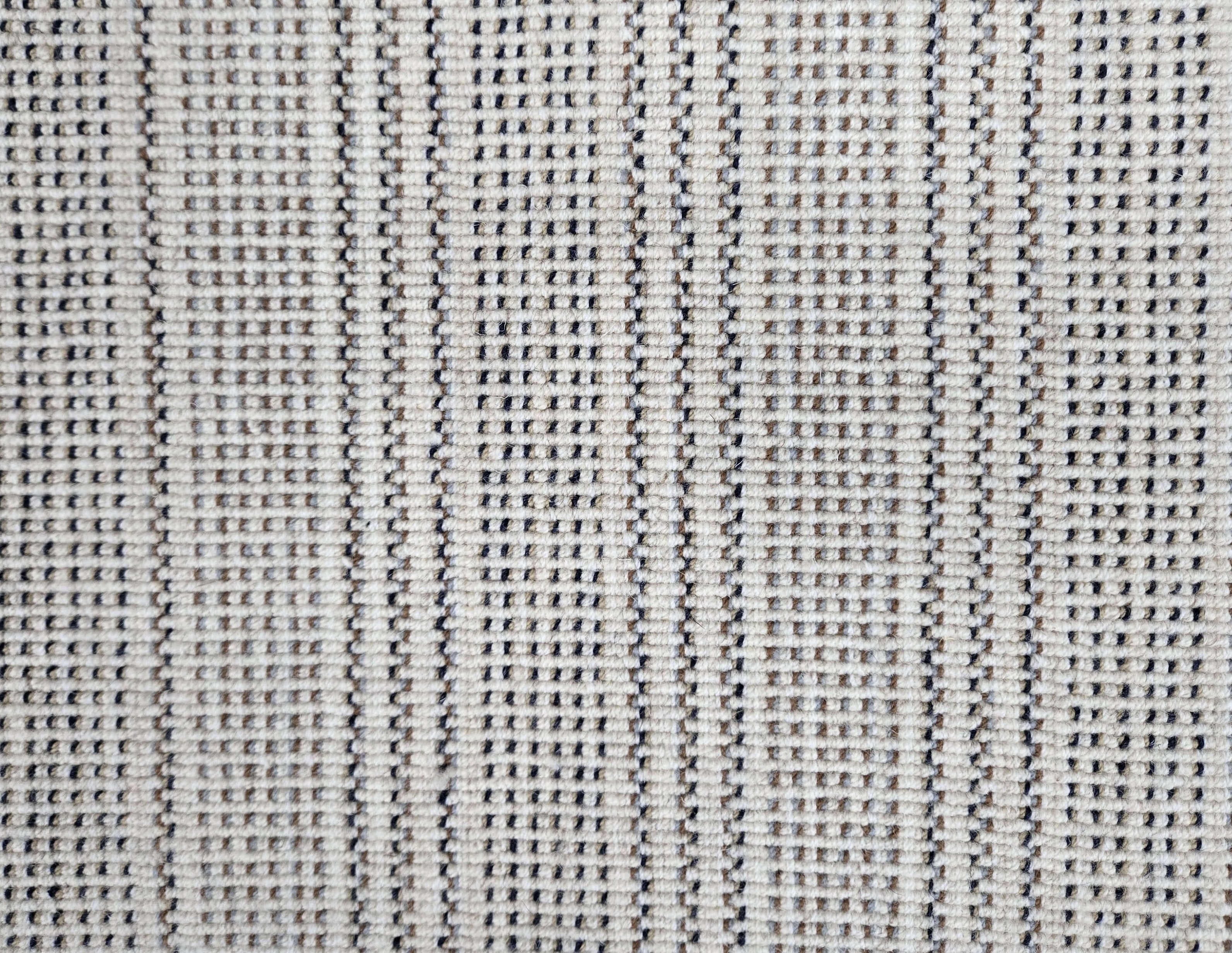 Broadloom carpet in dashed stripe pattern in shades of brown and grey with cream. 