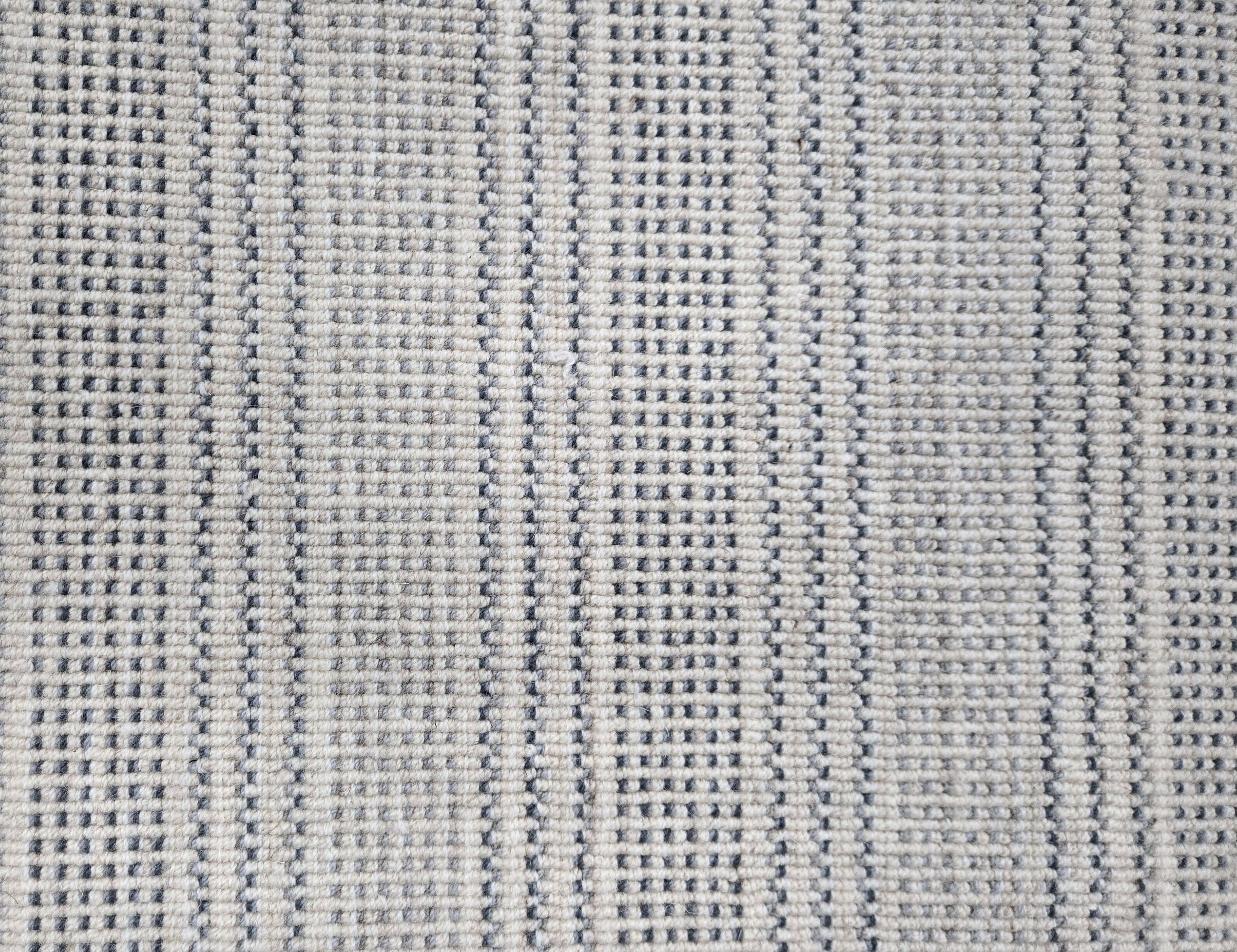 Broadloom carpet in dashed stripe pattern in shades of blue and grey with cream. 