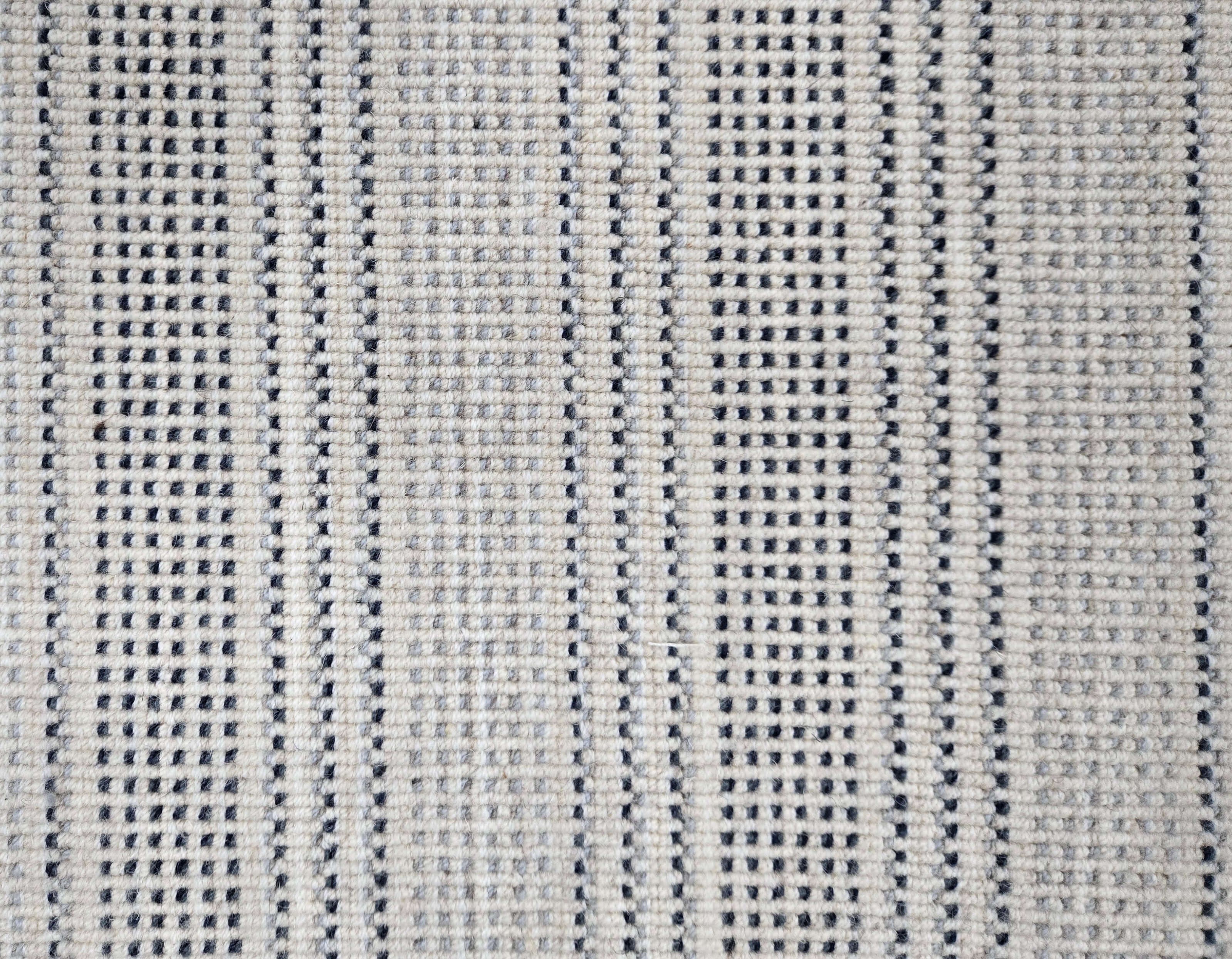 Broadloom carpet in dashed stripe pattern in shades of dark blue and grey with cream. 