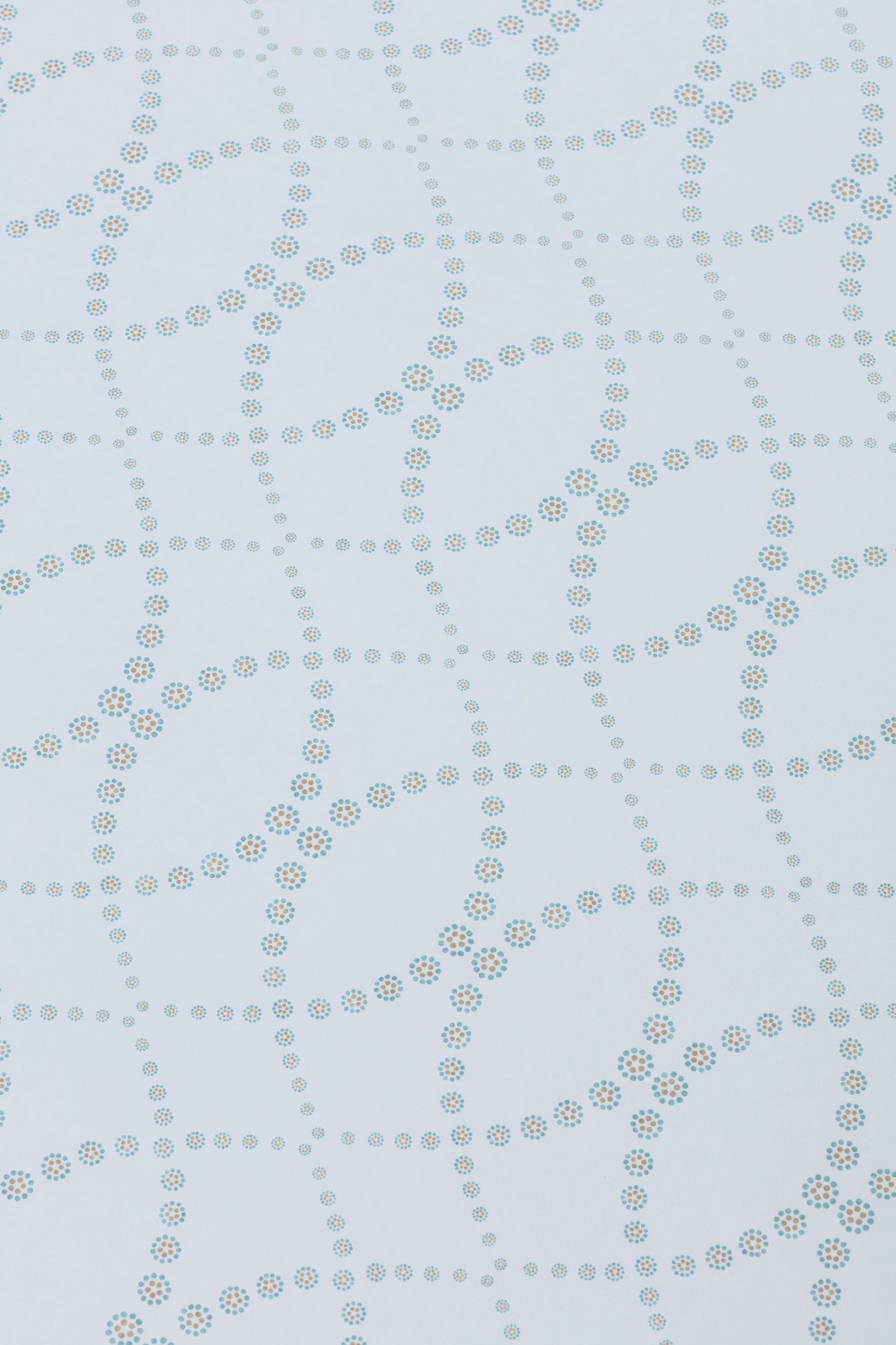 Detail of a wallpaper in a playful floral lattice print in aqua blue and tan on a white field.