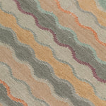 Close-up of fabric with wavy pattern in beige, turquoise, and orange.
