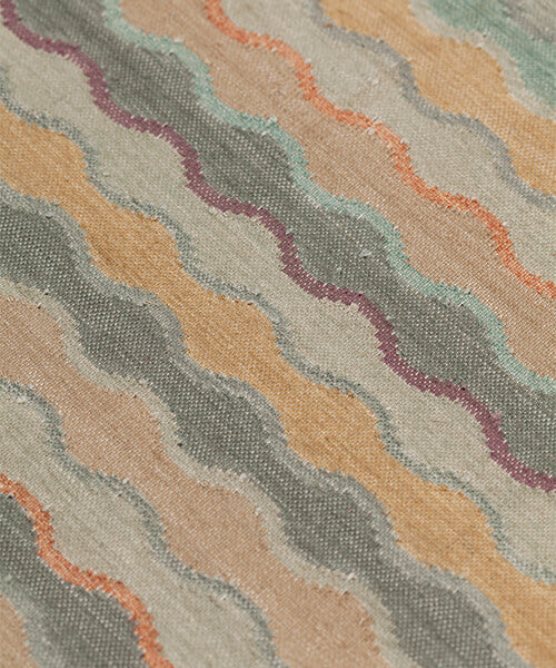 Close-up of fabric with wavy pattern in beige, turquoise, and orange.