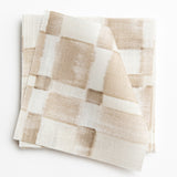 A stack of fabric swatches in a large-scale checked pattern in shades of cream and tan.