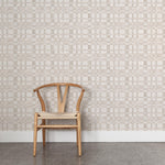 A wooden chair stands in front of a wall papered in a large-scale checked pattern in shades of cream and tan.