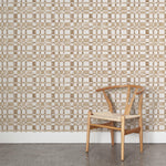 A wooden chair stands in front of a wall papered in a large-scale checked pattern in shades of brown and white.
