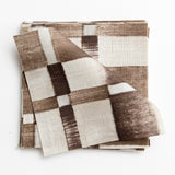 A stack of fabric swatches in a large-scale checked pattern in shades of cream and brown.