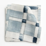 A stack of fabric swatches in a large-scale checked pattern in shades of cream and blue.