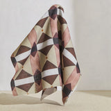 A large piece of draped fabric in a large-scale geometric grid in shades of tan, purple and brown on a white field.