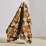 A large piece of draped fabric in a large-scale geometric grid in shades of brown, tan and gray.