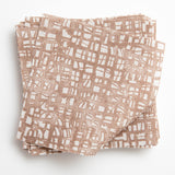 A stack of fabric swatches in a textural wicker pattern in mottled brown on a white field.