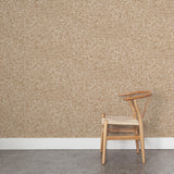 A wooden chair stands in front of a wall papered in a textural wicker pattern in mottled tan on a white field.
