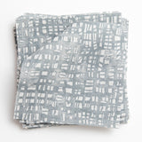 A stack of fabric swatches in a textural wicker pattern in mottled gray on a white field.