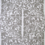 Detail of fabric in a large-scale tree and leaf print in white on a light gray field.