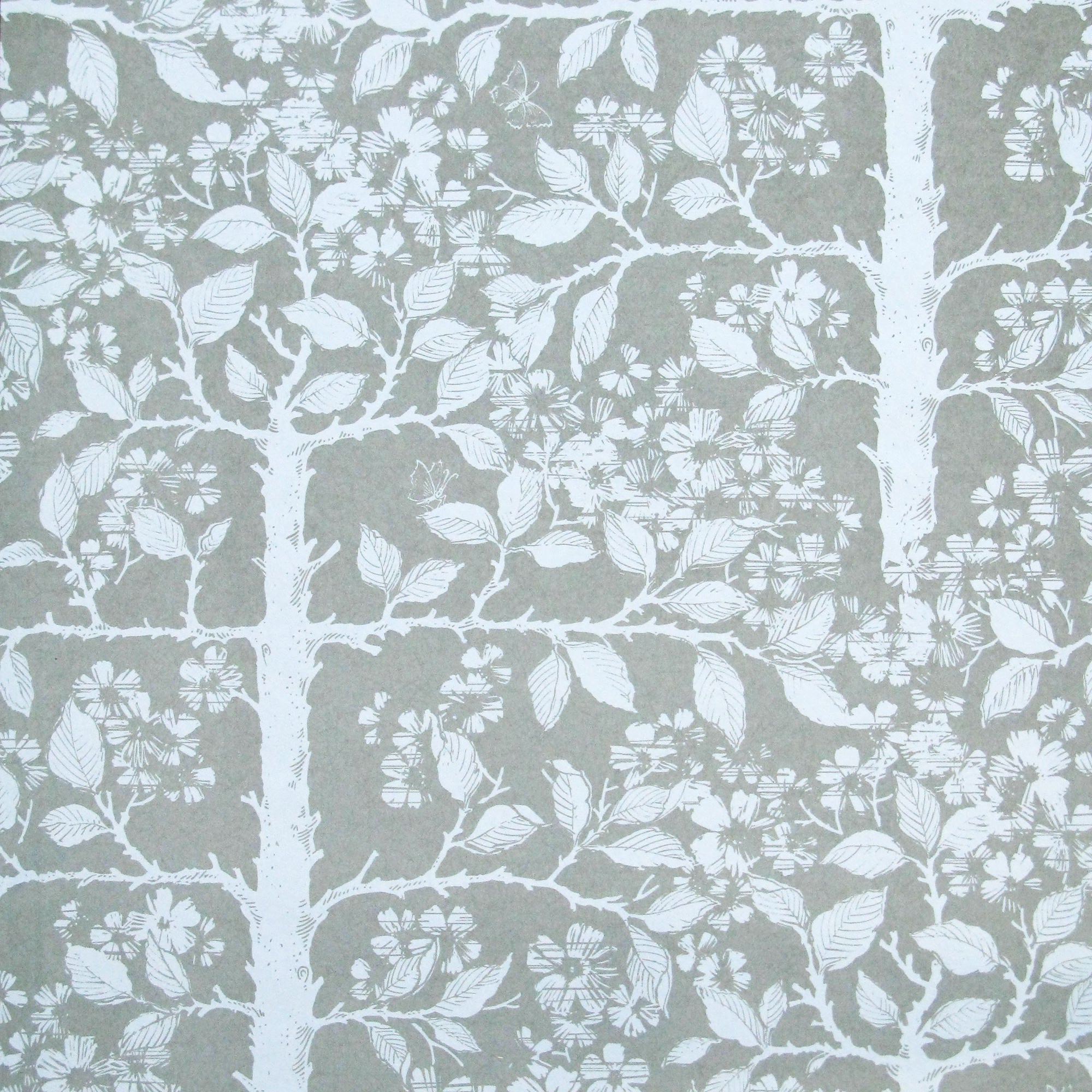 Detail of wallpaper in a large-scale tree and leaf print in white on a light gray field.
