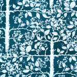 Detail of wallpaper in a large-scale tree and leaf print in white on an indigo field.