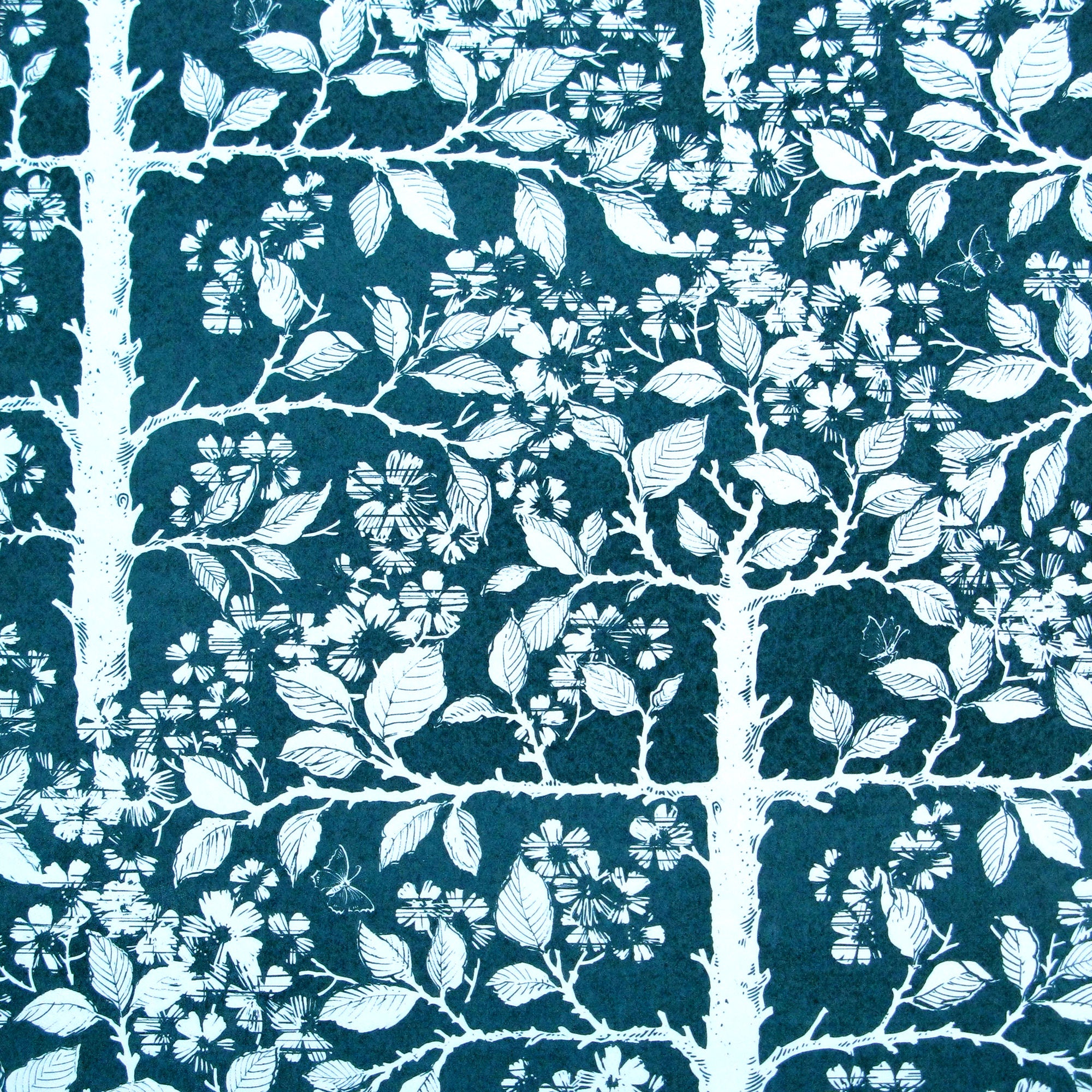Detail of wallpaper in a large-scale tree and leaf print in white on an indigo field.