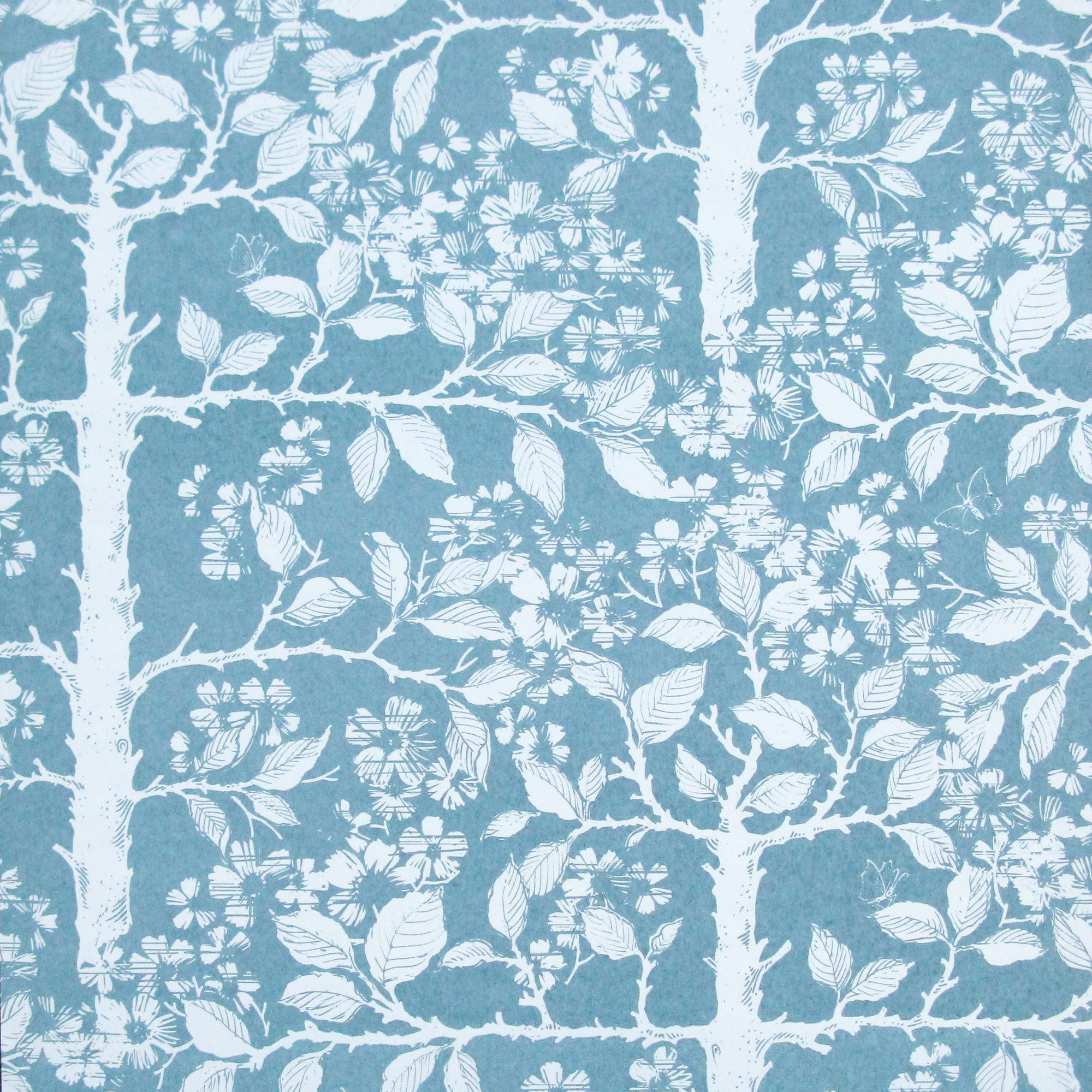 Detail of wallpaper in a large-scale tree and leaf print in white on a light blue field.