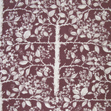 Detail of fabric in a large-scale tree and leaf print in cream on a maroon field.