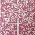 Detail of fabric in a large-scale tree and leaf print in cream on a pink field.