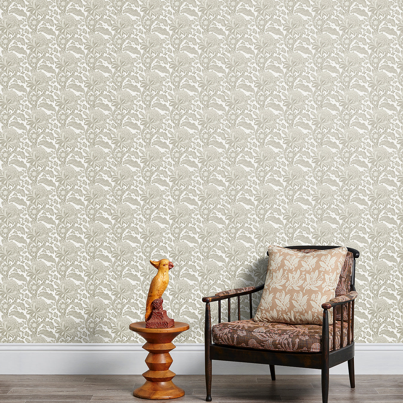 Armchair and end table in front of a wall papered in a repeating botanical print in cream and white.