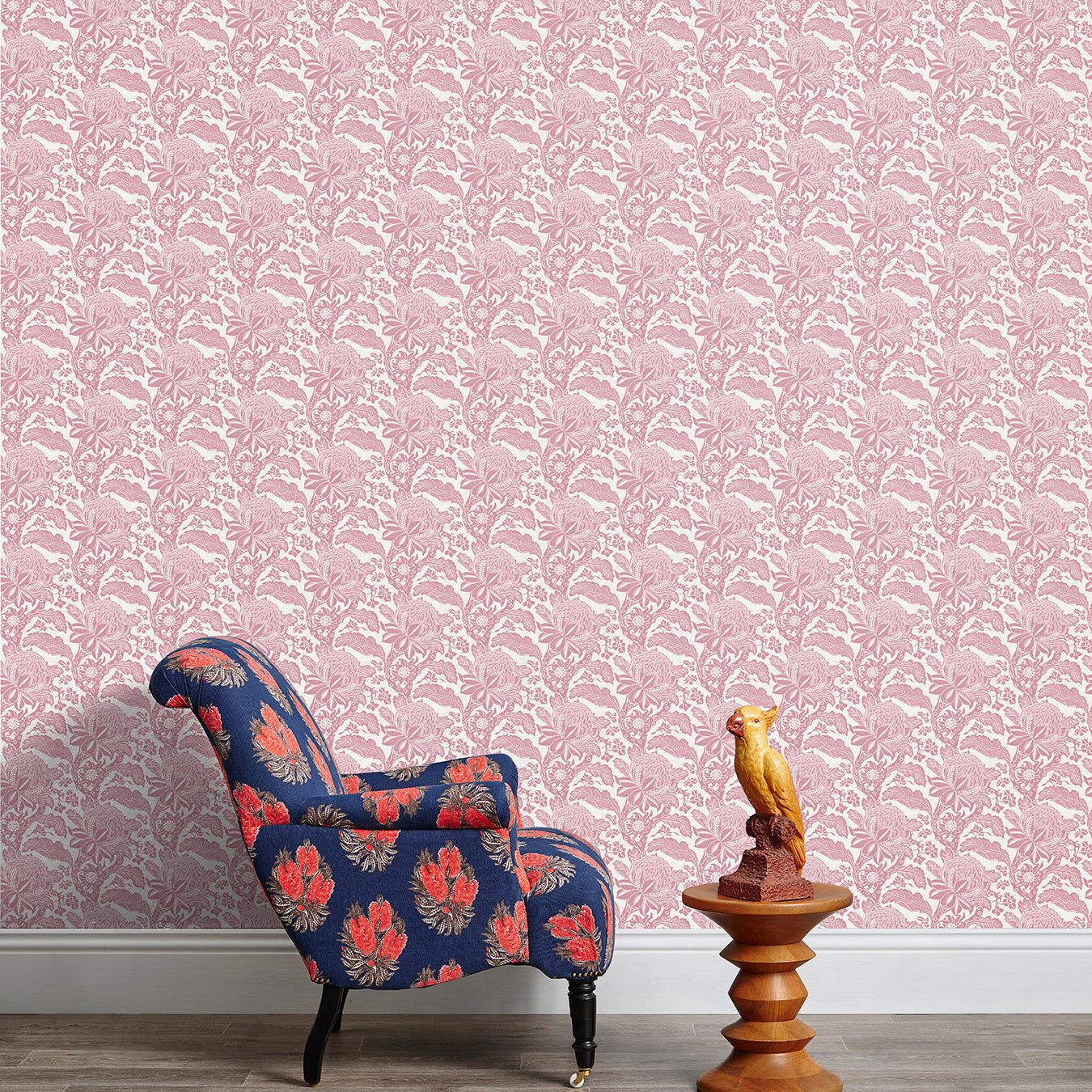 Armchair and end table in front of a wall papered in a repeating botanical print in pink and white.