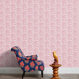 Armchair and end table in front of a wall papered in a repeating botanical print in pink and white.