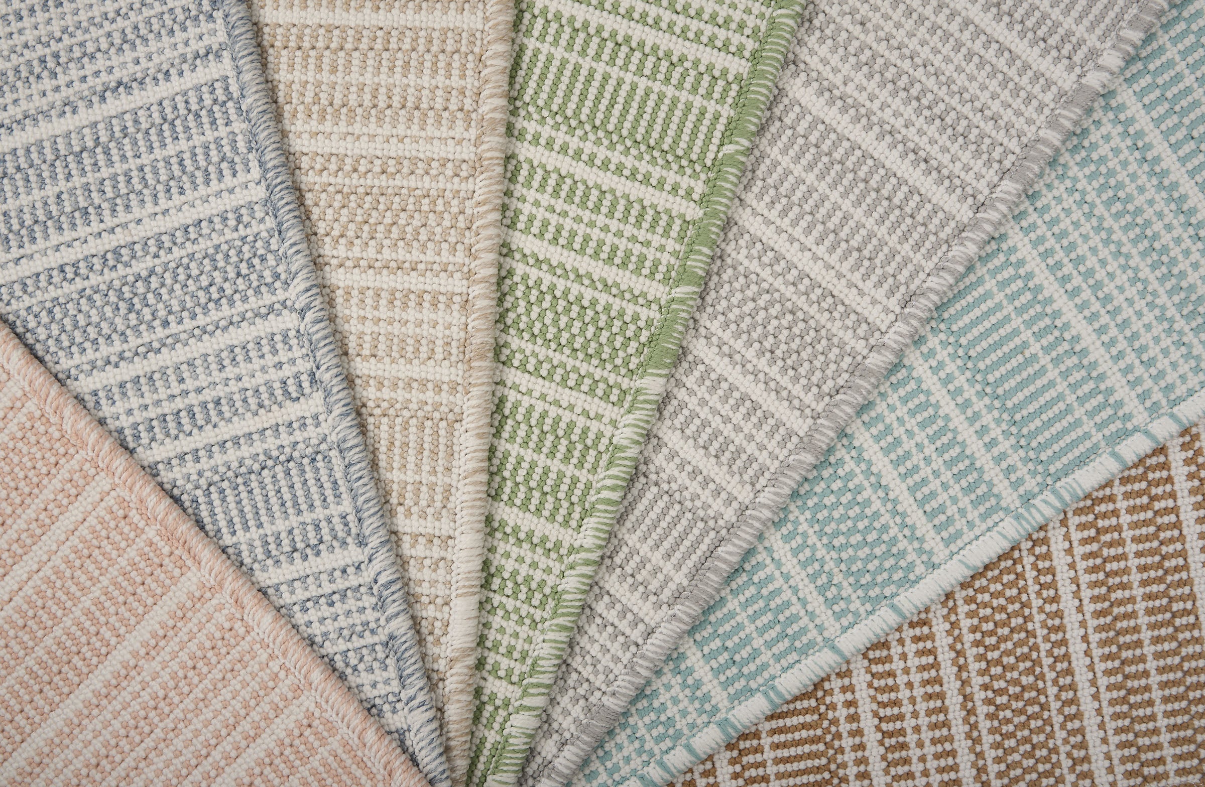 Stack of broadloom carpets in a textural stripe in a range of colors. 