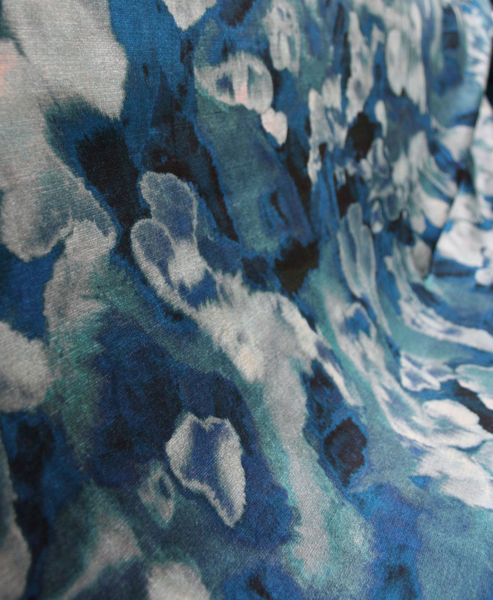 Close-up of velvet fabric in an abstract paint print in shades of blue, navy and turquoise.