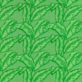 Detail of fabric in a dense leaf print in shades of green on a green field.