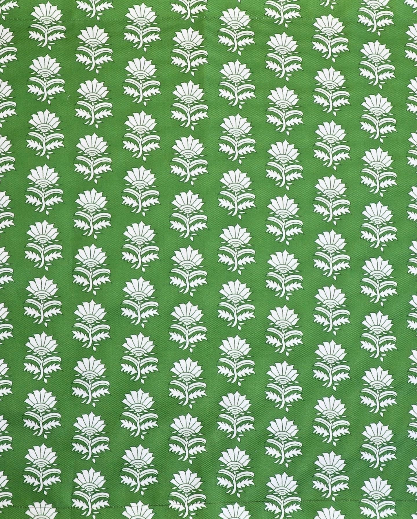 Detail of fabric in a repeating thistle print in white and green on a green field.