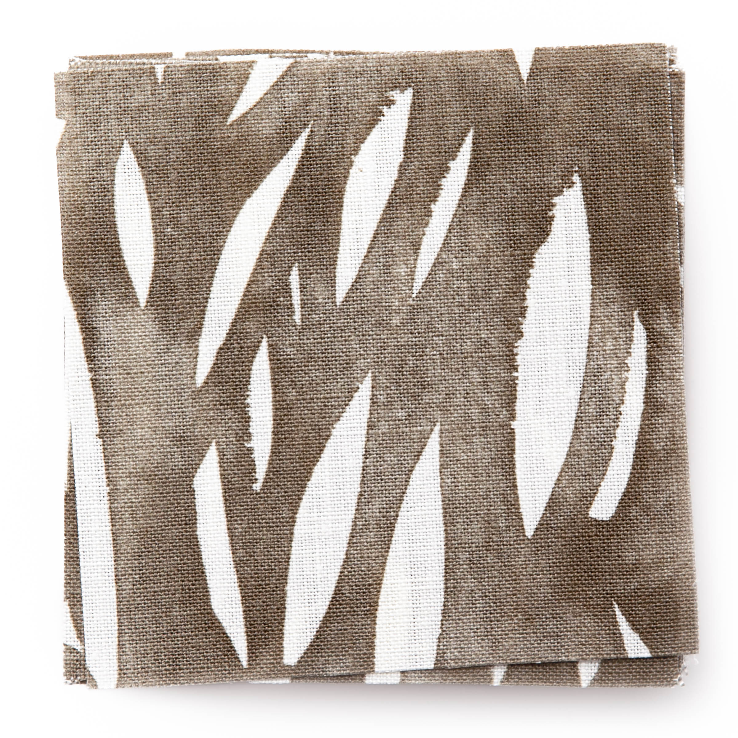 A stack of fabric swatches in an abstract leaf pattern in white on a brown watercolor field.