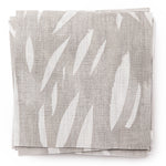 A stack of fabric swatches in an abstract leaf pattern in white on a light gray watercolor field.