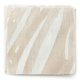 A stack of fabric swatches in an abstract leaf pattern in white on a cream watercolor field.