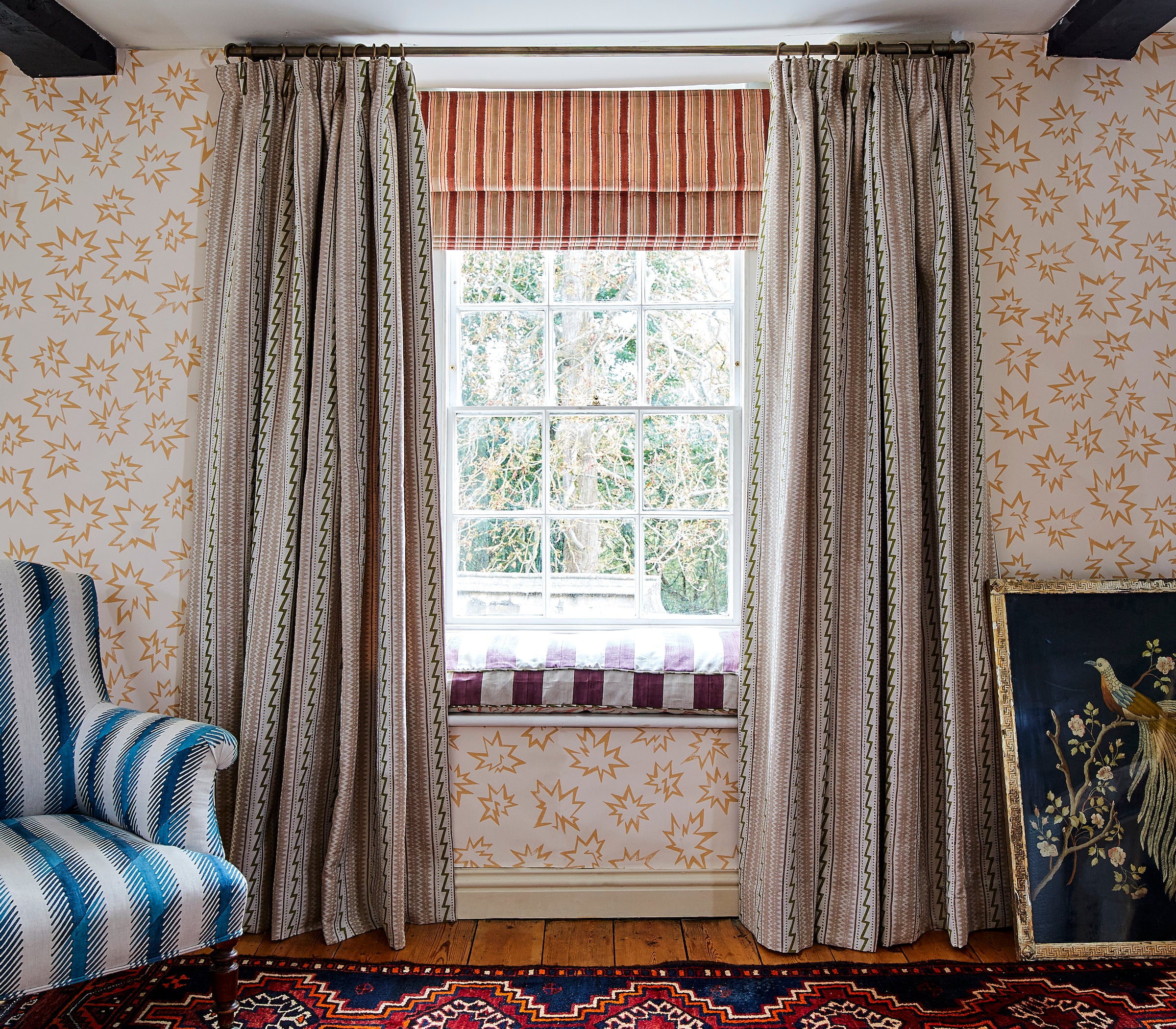 Chabby-chic living room with a large window and a wall papered in a playful cartoon "Pow" print in pink and cream.