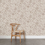 A wooden chair stands in front of a wall papered in a playful animal and tree print in brown on a cream field.