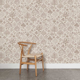 A wooden chair stands in front of a wall papered in a playful animal and tree print in brown on a cream field.