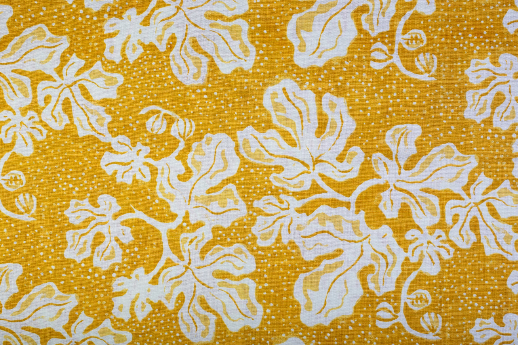 Detail of fabric in a playful botanical print in yellow and white on a bright yellow field.