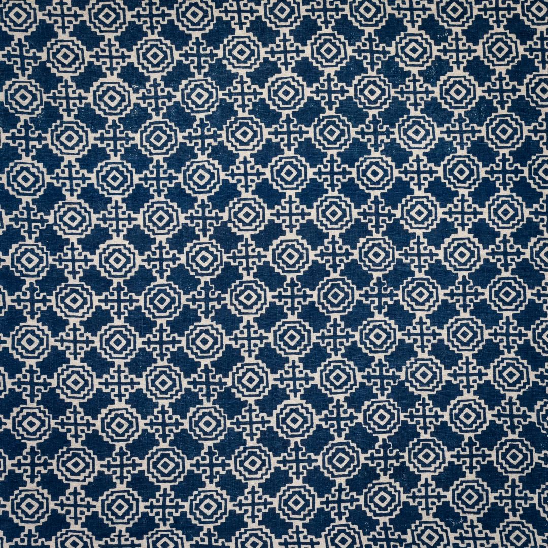 Detail of fabric in a repeating geometric print in cream on a navy field.