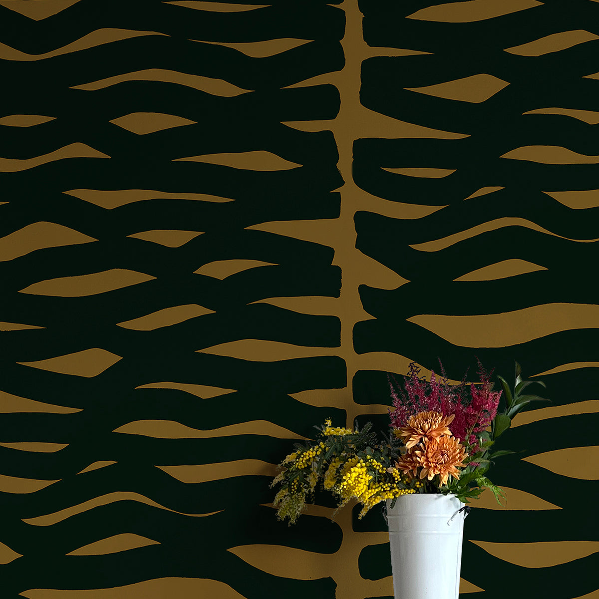 A vase of flowers stands in front of a wall papered in an abstract zigzag pattern in black on a brown field.