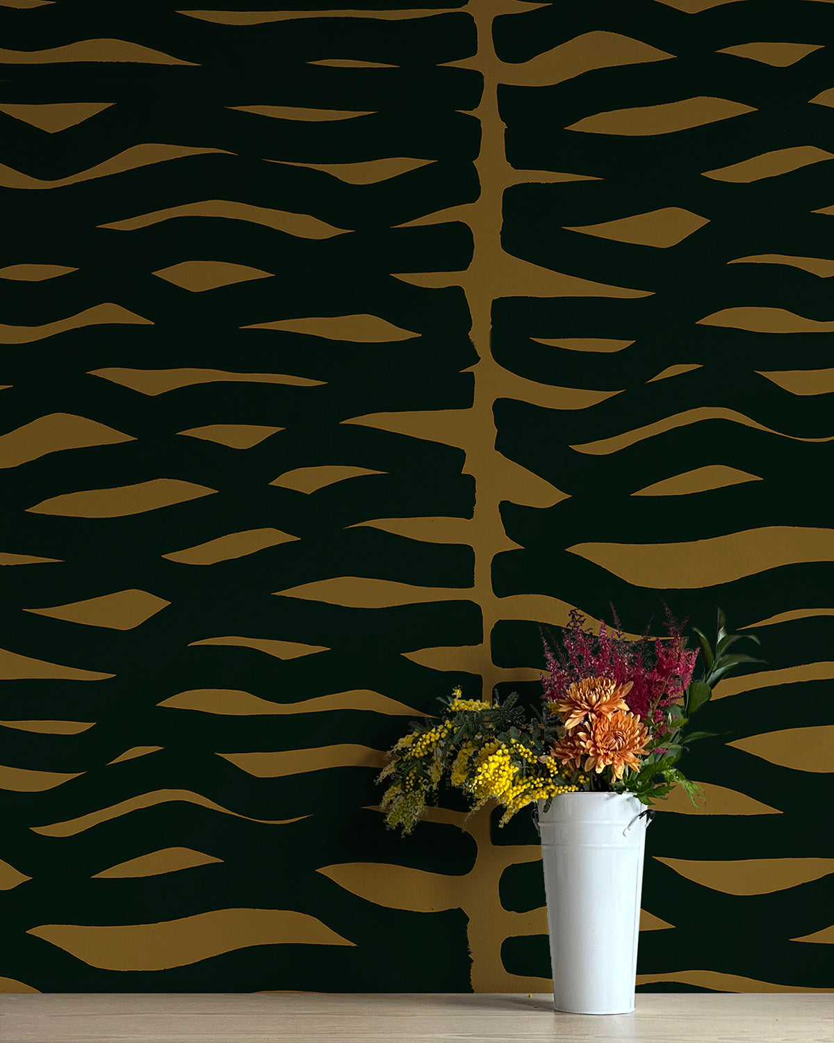 A vase of flowers stands in front of a wall papered in an abstract zigzag pattern in black on a brown field.