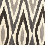 Detail of fabric in a geometric ikat print in shades of gray on a tan field.