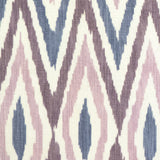 Detail of fabric in a geometric ikat print in shades of purple and navy on a tan field.