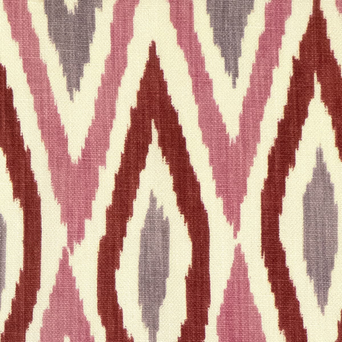 Detail of fabric in a geometric ikat print in shades of purple, pink and red on a tan field.