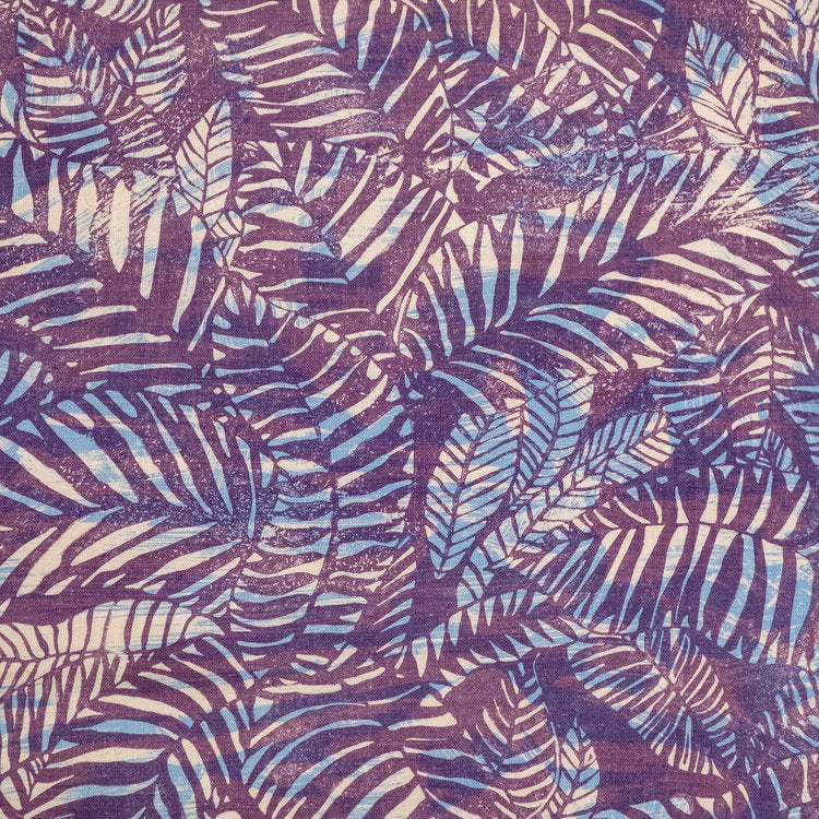 Detail of fabric in a dense leaf print in mottled cream and blue on a purple field.