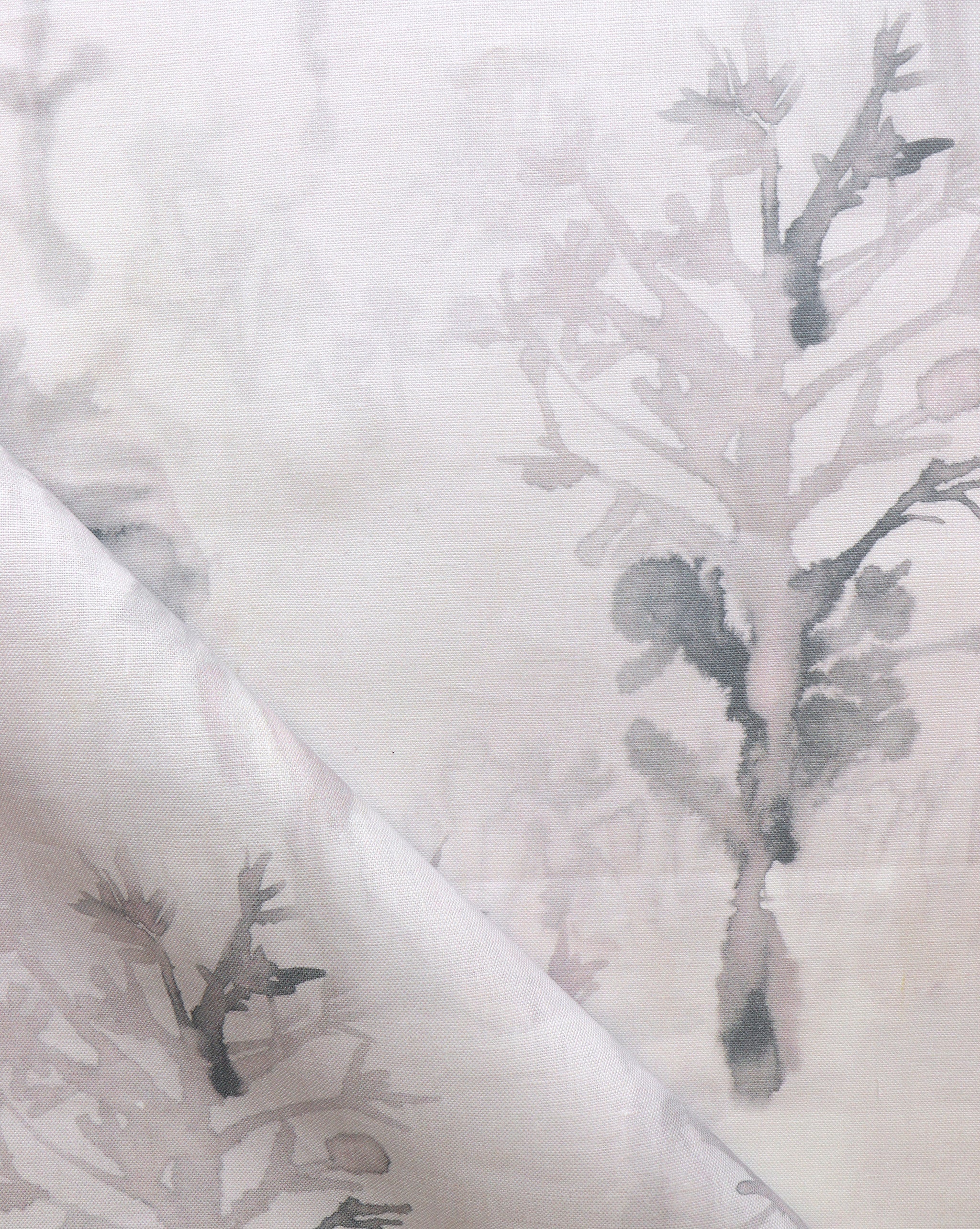 Detail of draped fabric yardage in an abstract botanical print in shades of light gray and pink on a cream field.