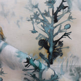 Detail of draped fabric yardage in an abstract botanical print in shades of turquoise, gray and gold on a cream field.