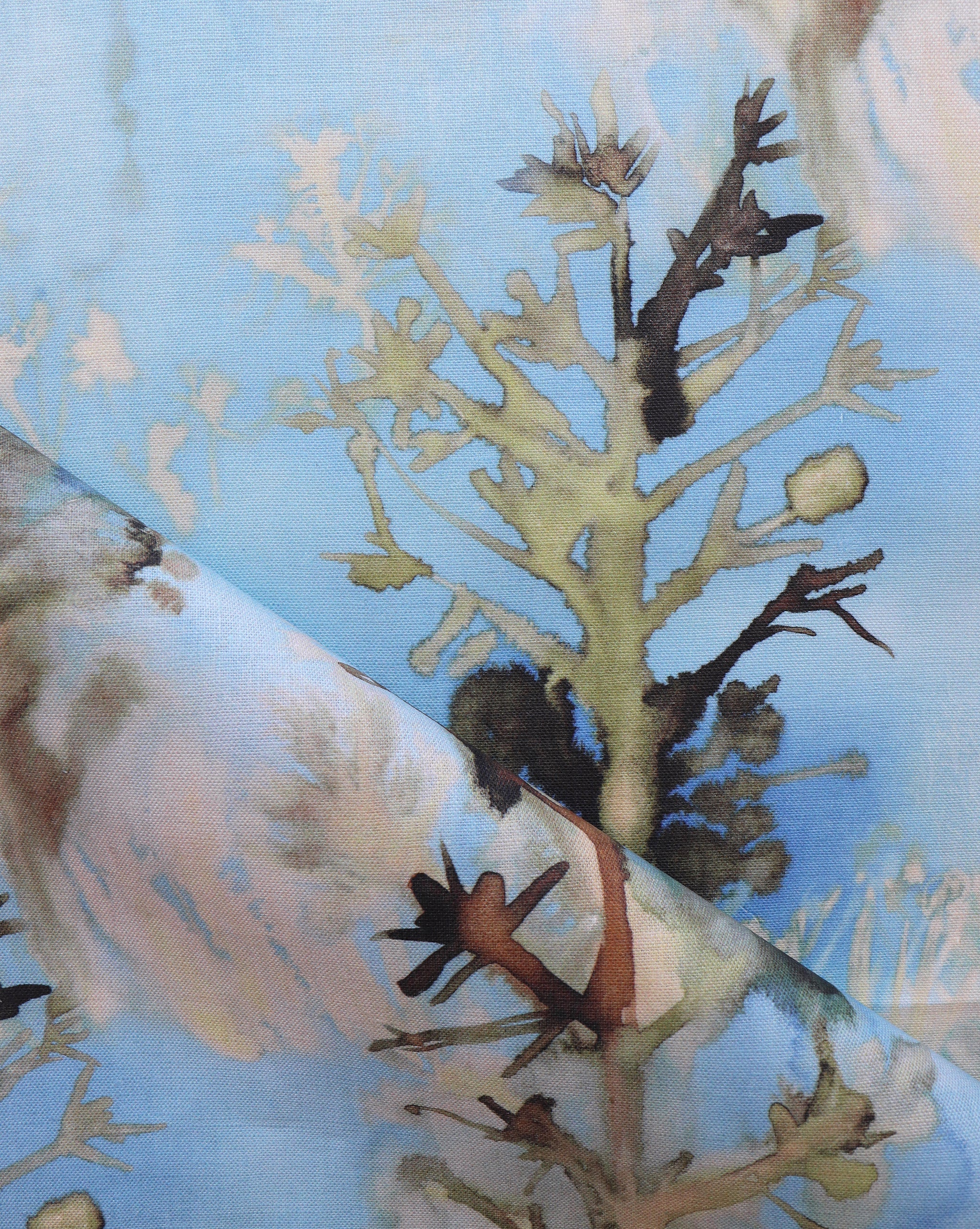 Detail of draped fabric yardage in an abstract botanical print in shades of tan and gray on a blue field.