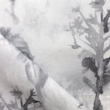 Detail of draped fabric yardage in an abstract botanical print in shades of gray and black on a white field.