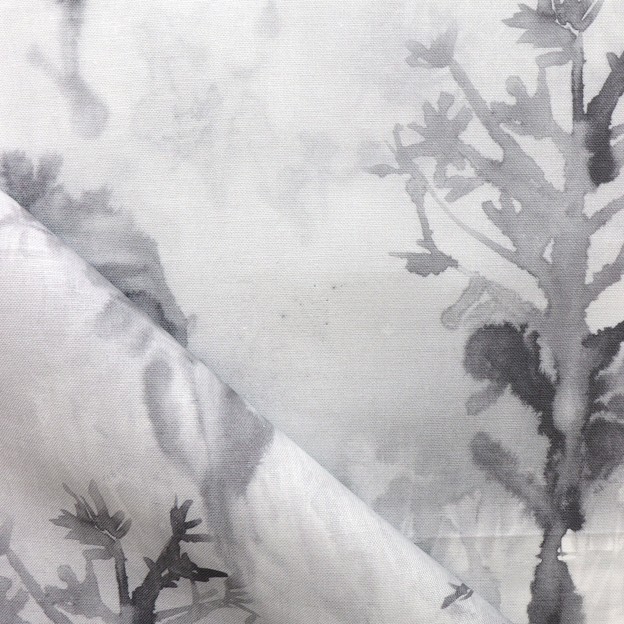 Detail of draped fabric yardage in an abstract botanical print in shades of gray and black on a white field.