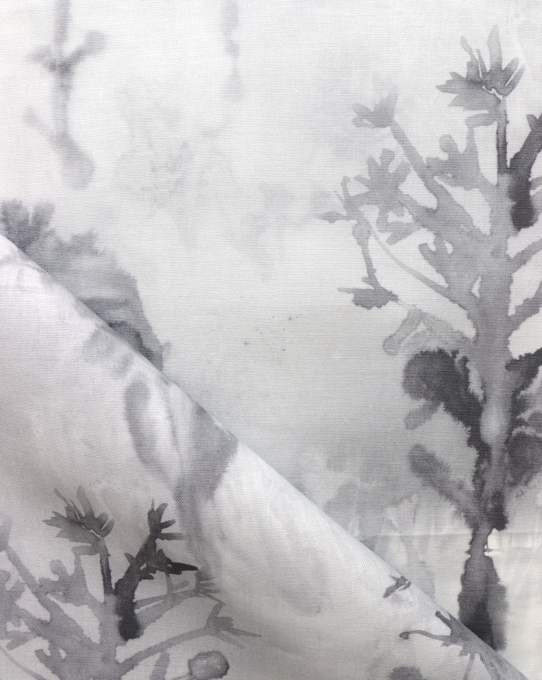 Detail of draped fabric yardage in an abstract botanical print in shades of gray and black on a white field.